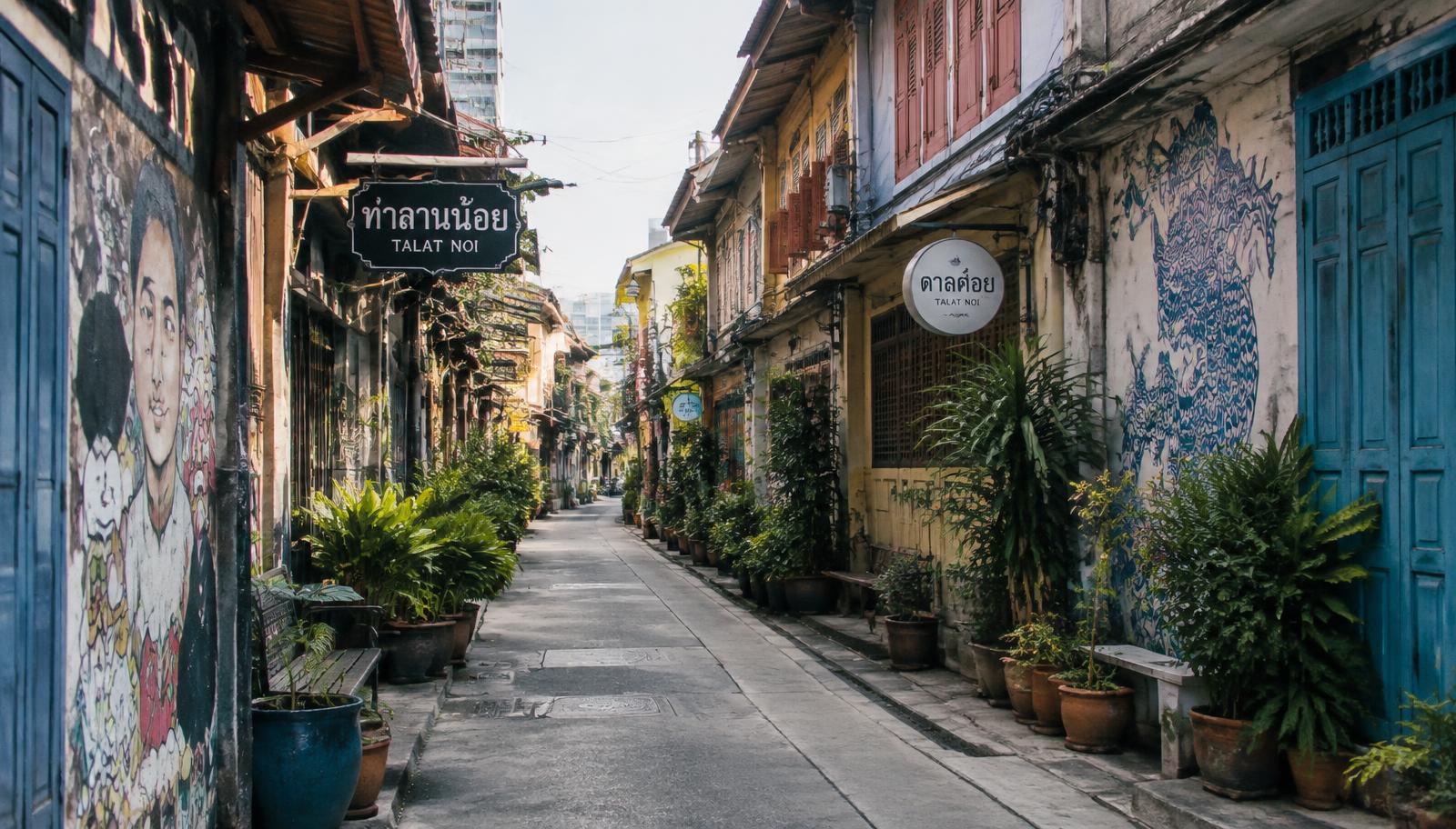 A quiet lane in Talat Noi lined with old shophouses, potted plants and street art
