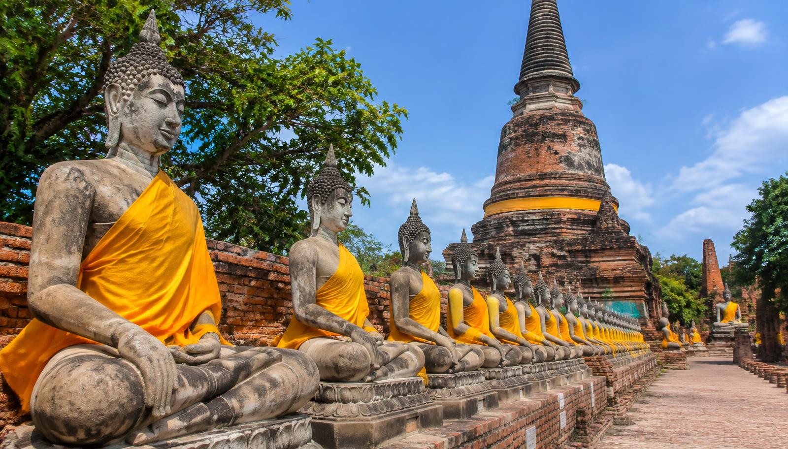 Rows of saffron-draped seated Buddha images beside the large chedi at Wat Yai Chai Mongkhon