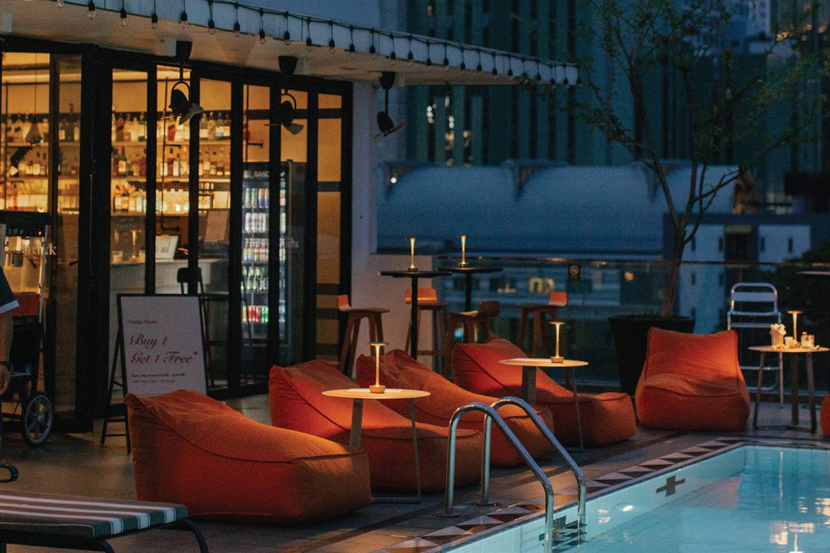 The Drink rooftop bar at Vince Hotel with poolside lounge seating in the evening