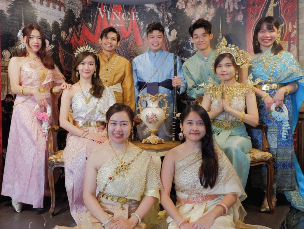 Guests dressed in traditional Thai costume posing together at Vince Hotel