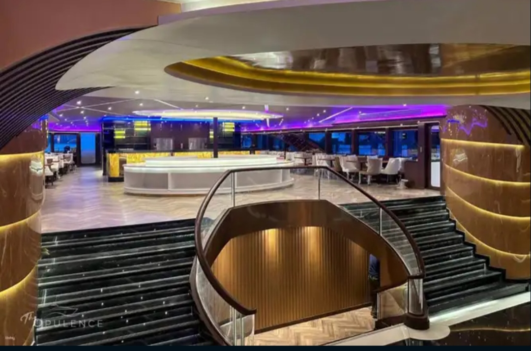 The Opulence Cruise dining lounge with sweeping staircases and illuminated bar