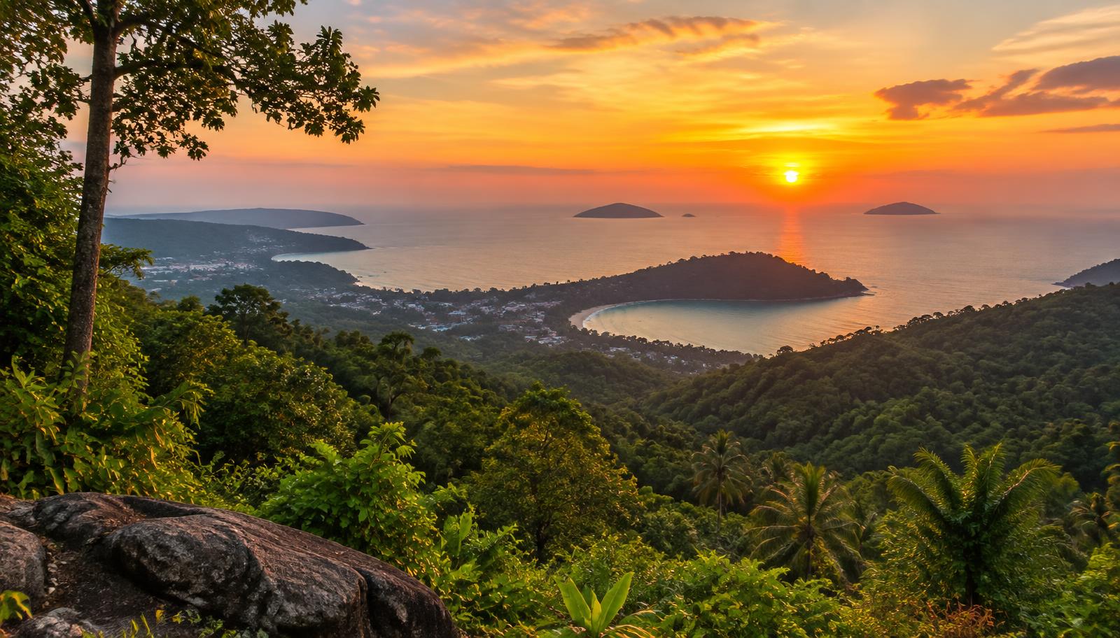 Sunset over a bay and small islands seen from a forested hilltop viewpoint in Phuket