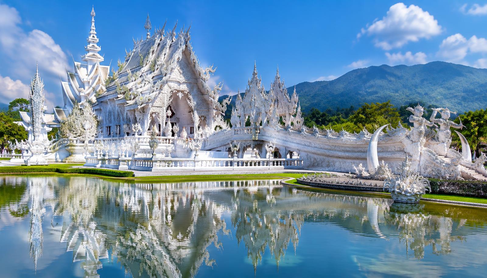 The ornate White Temple, Wat Rong Khun, reflected in a pond in Chiang Rai, Thailand